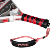 Eine Nahaufnahme des Griffs des NOX VK10 QUANTUM 3K Padelschlägers von Aranzazu Osoro, der seinen schwarz-roten Griff hervorhebt, der mit einer roten Handschlaufe mit dem „Nox“-Branding verziert ist. Das Design enthält strukturierte Abschnitte, um Griffigkeit und Handhabung zu verbessern, während der Schlägerkopf neben technischen Details deutlich seinen Markennamen zeigt.